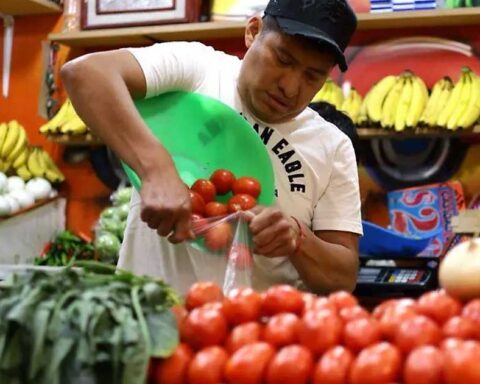 Vendedor despechando jitomate en un mercado.