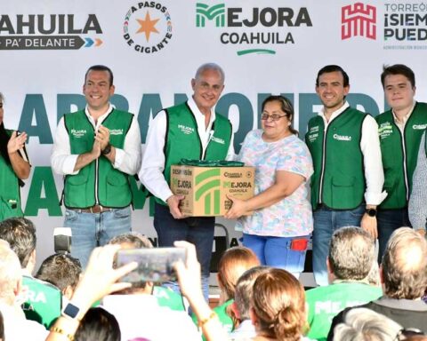 Alcalde entregando una caja de despensa a una mujer, rodeados de vecinos en Torreón.