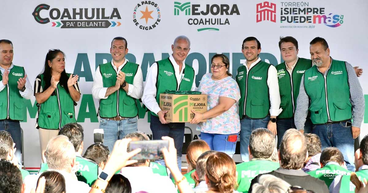 Alcalde entregando una caja de despensa a una mujer, rodeados de vecinos en Torreón.