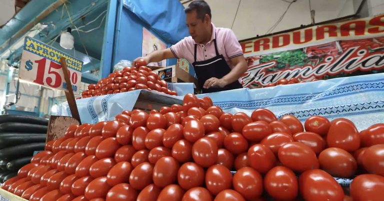 Comerciante vendiendo jitomate en un mercado.