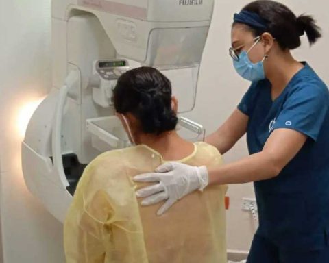 Enfermera guiando a una mujer de espaldas hacia el estudio de mastografía.