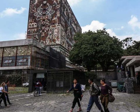 Jóvenes caminando frente al edificio principal de la UNAM.