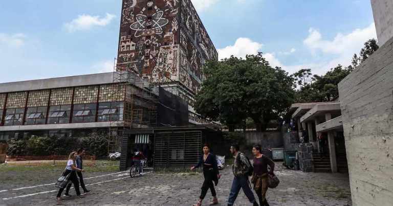 Jóvenes caminando frente al edificio principal de la UNAM.