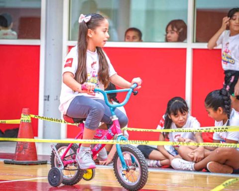 Una niña en una bicicleta; de fondo, más niñas.